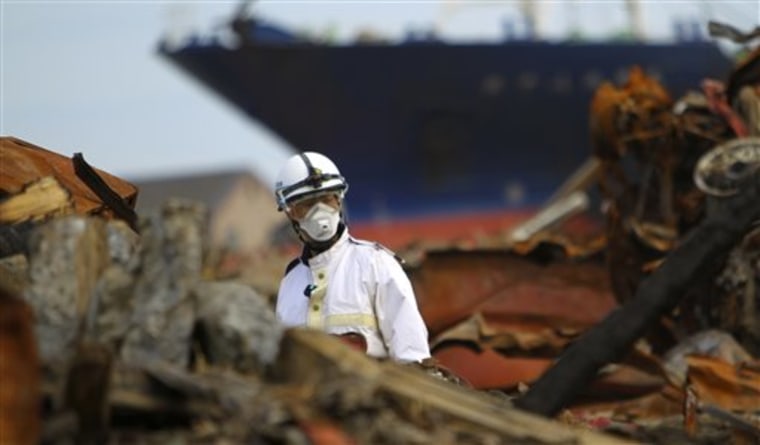 A police officer walks in rubble at recovery operation in the area destroyed by the March 11 earthquake and tsunami in Kesennuma,  Miyagi Prefecture, northeastern Japan, Saturday, May 7, 2011.  (AP Photo/Junji Kurokawa)